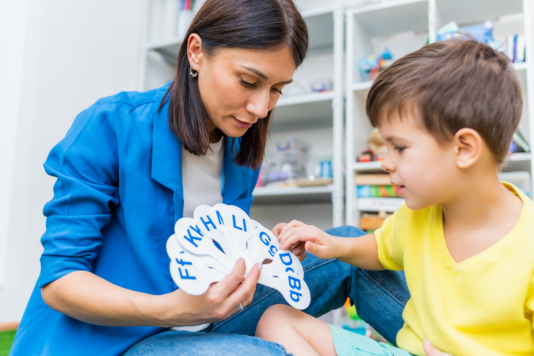 child with a speech therapist is taught to pronounce the letters, words and sounds correctly.