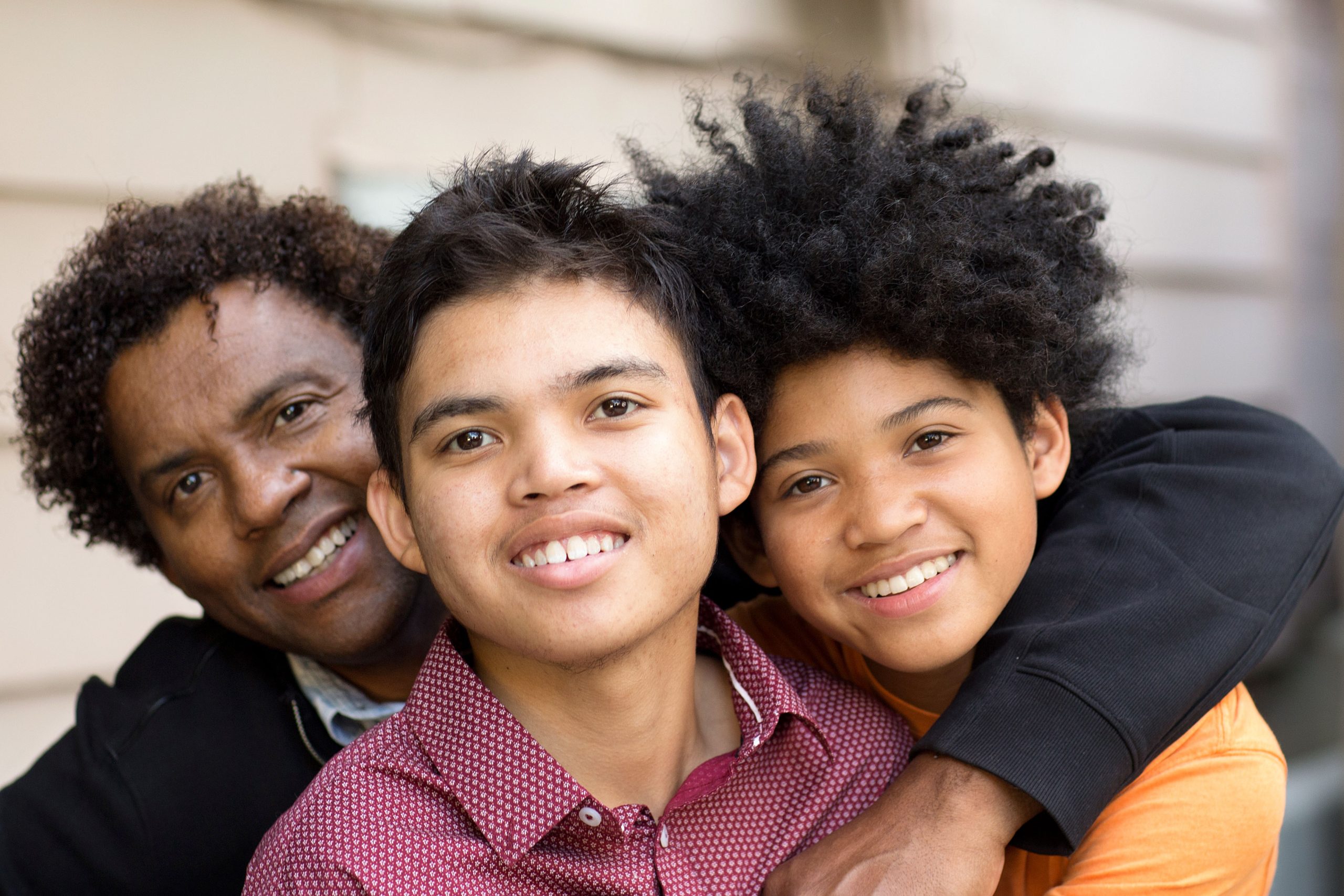 Portrait of a father hugging his sons.