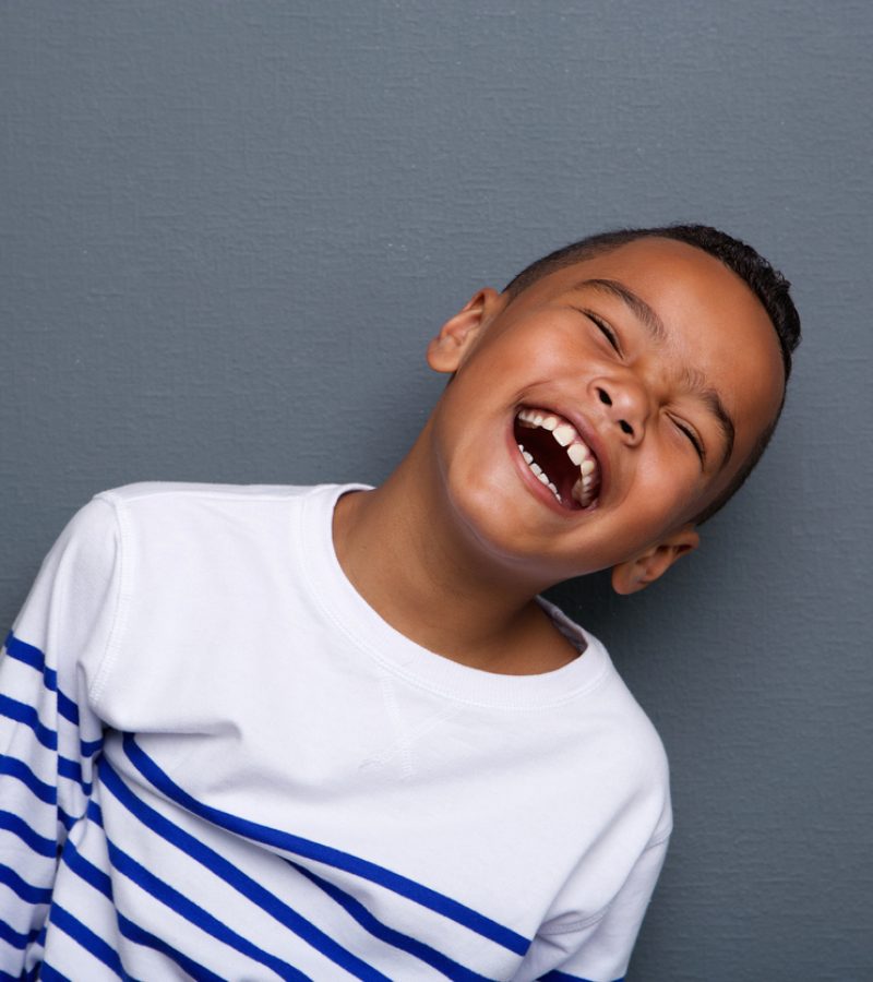 Close up portrait of a happy little boy smiling on gray background